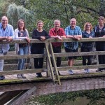 Der erweiterte Vorstand des 1. Passauer Tauchsportclub steht auf einer Holzbrücke über einem Fluss